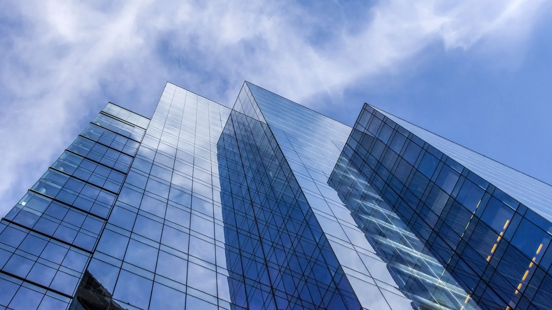 Glass tower reflecting clouds and sky