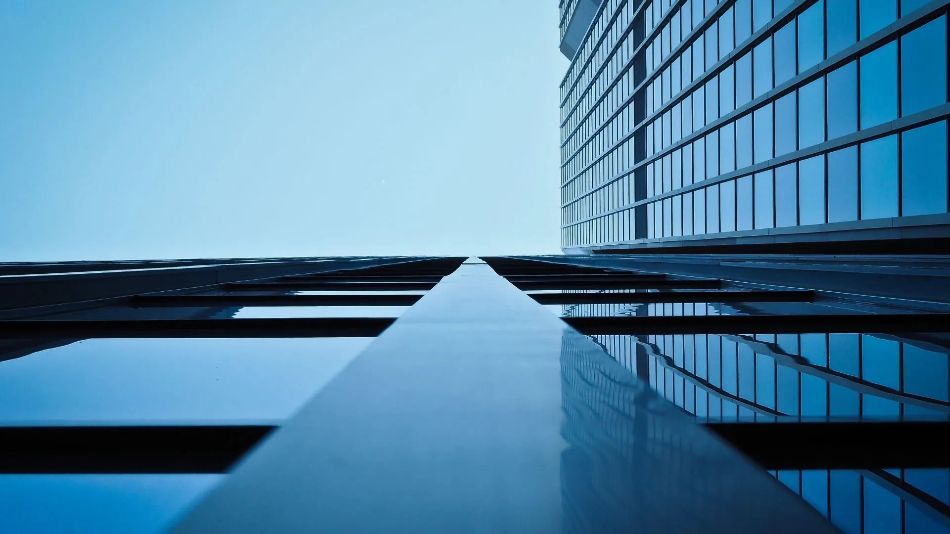 Symmetrical upward view of a glass office tower against a clear sky